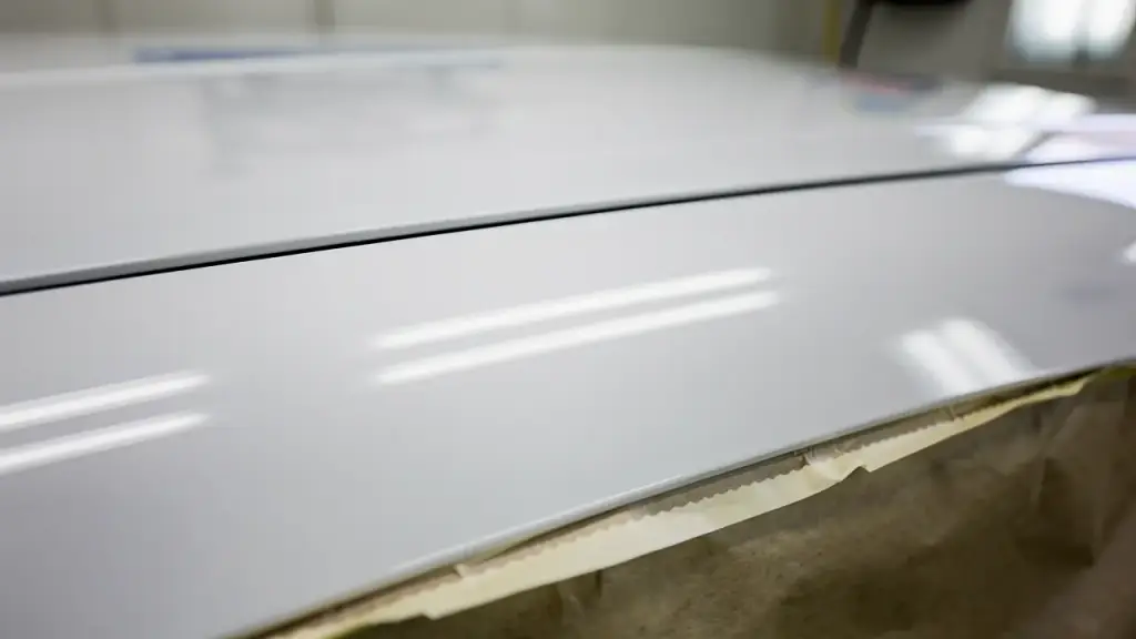 Two white refinished panels meeting at a tight panel gap, masking tape along the lower edge